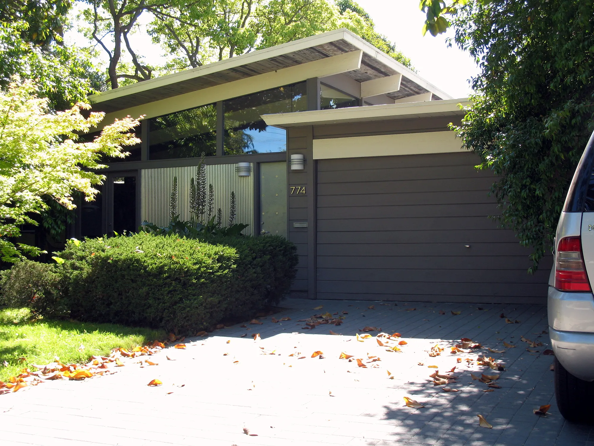 A one-story Eichler house in Palo Alto with a low-pitched roof, a band of clerestory windows above a closed street front, and a wide garage door.