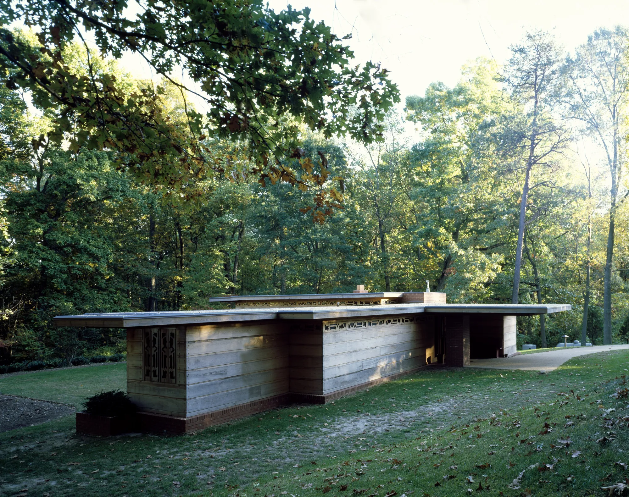 A low wood and brick house with a flat roof among trees at Woodlawn in Virginia.