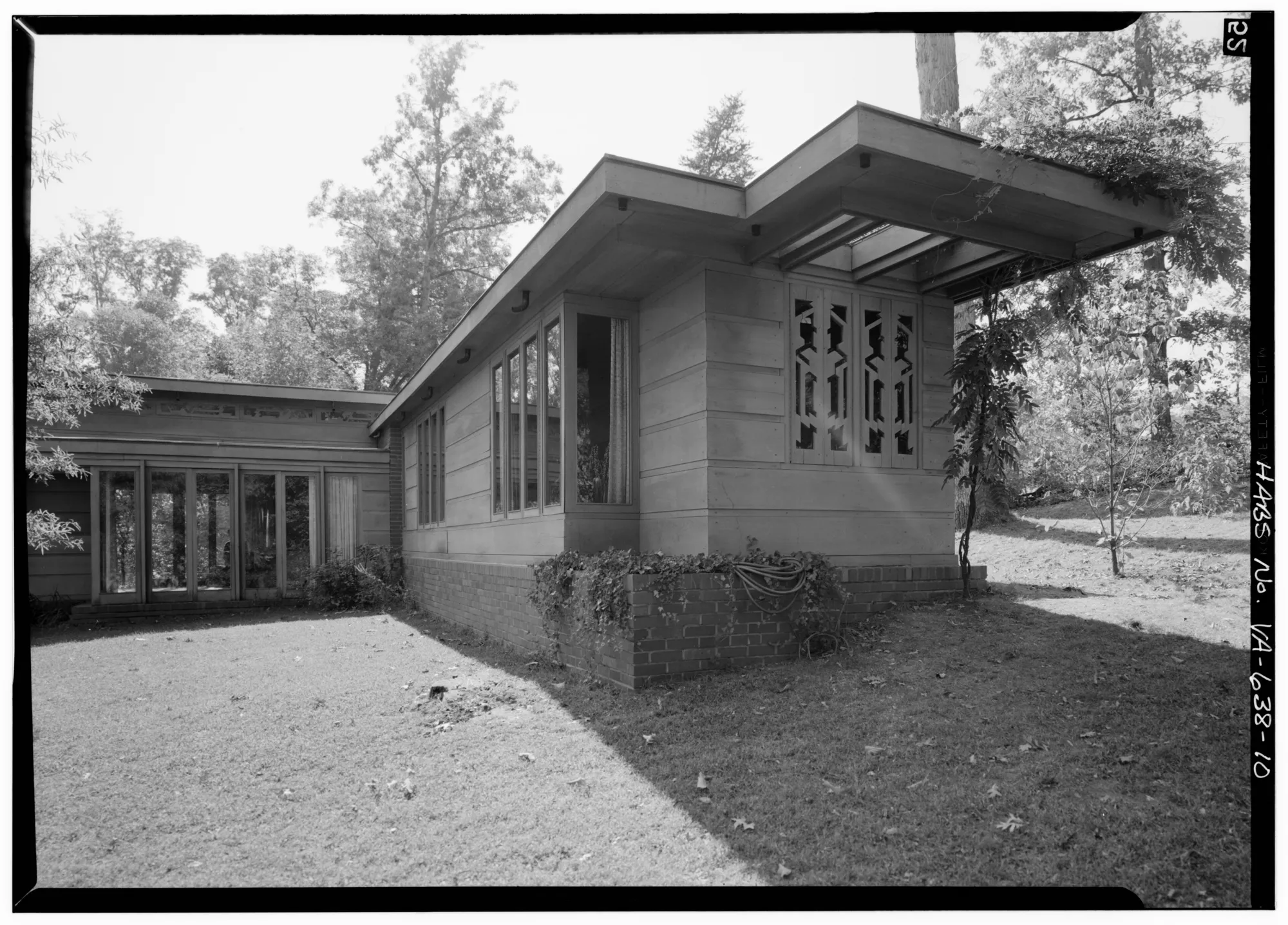 The east and north sides of the wood-and-brick Pope-Leighey House among trees.