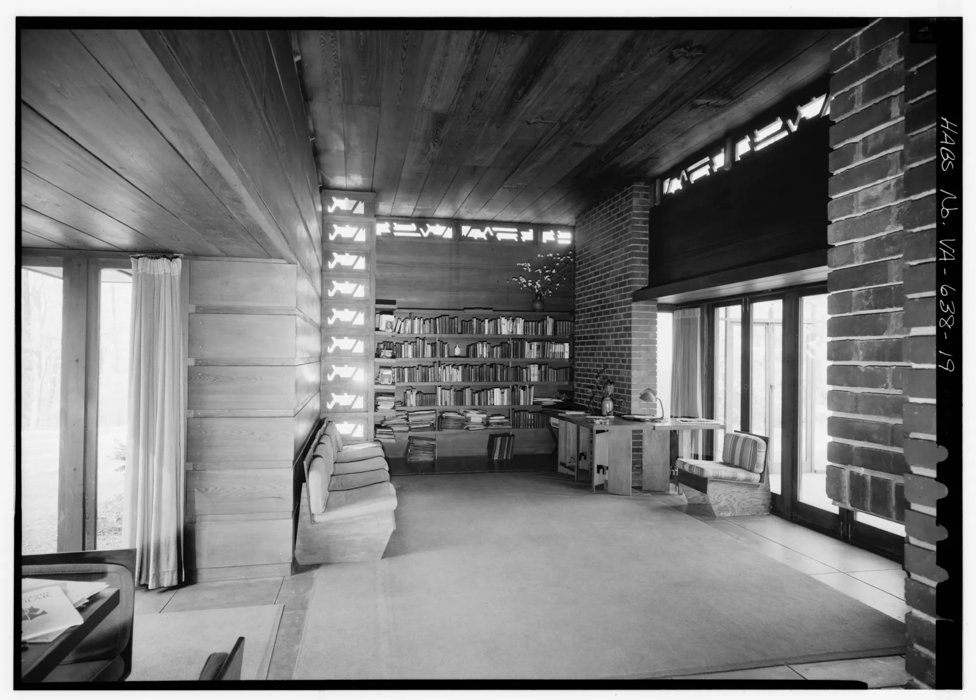 The living room of the Pope-Leighey House, with brick walls, built-in shelves and a high ceiling.